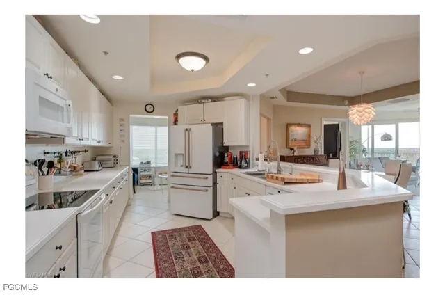 a large kitchen with kitchen island a sink a stove a refrigerator and white cabinets
