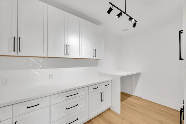 a view of a hallway with wooden floor and a bathroom