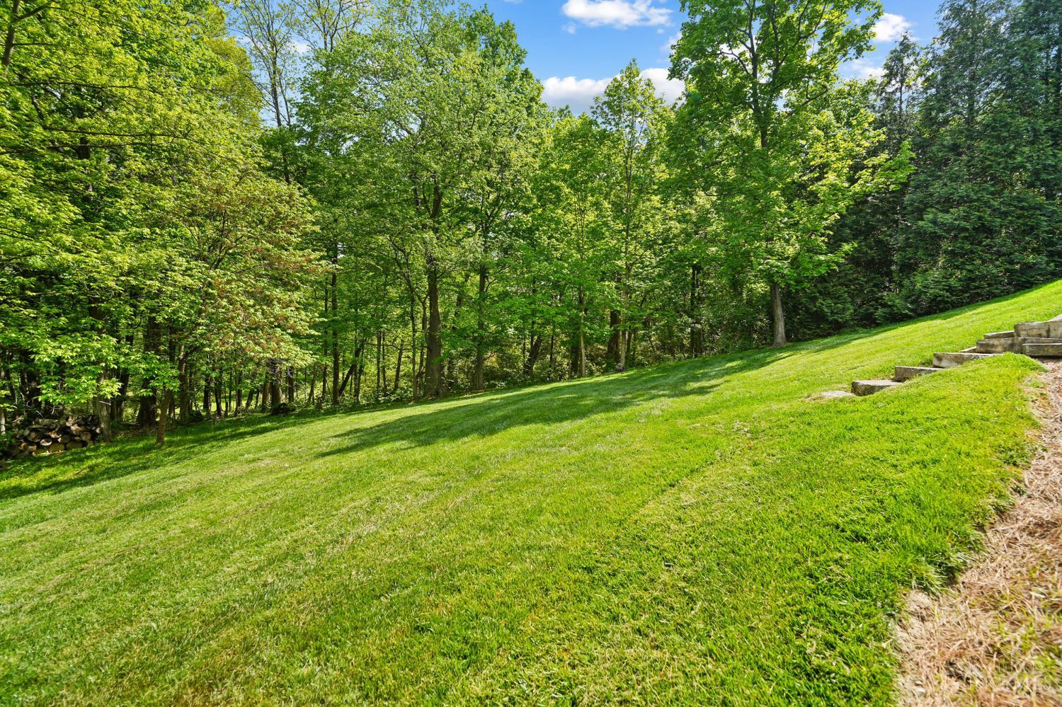2780 Walsh Road Cincinnati, OH 45208 - Photo 66 of 77 The rear yard offers a beautiful blend of structure and natural serenity, with thoughtfully placed stepping stones and a stone stairway that gently guide you to a lush, expansive lawn. Set on a private 1.5-acre lot, the property is surrounded by mature trees, creating a peaceful, park-like setting with both open green space and wooded privacy—ideal for outdoor enjoyment, play or quiet retreat.