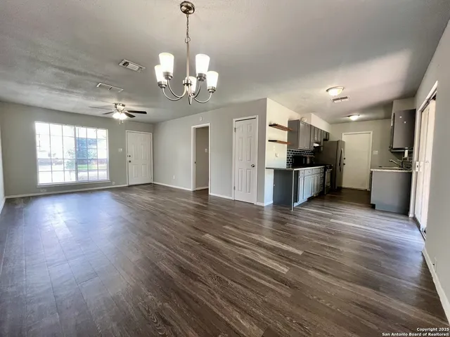 a view of a big room with wooden floor and windows