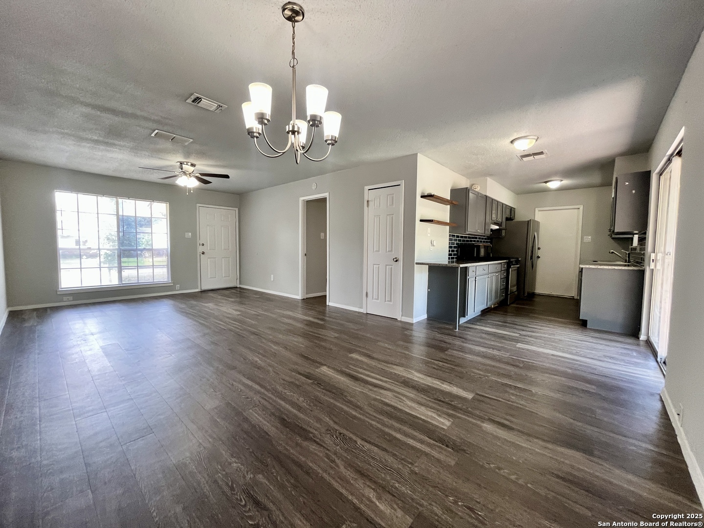 a view of a big room with wooden floor and windows