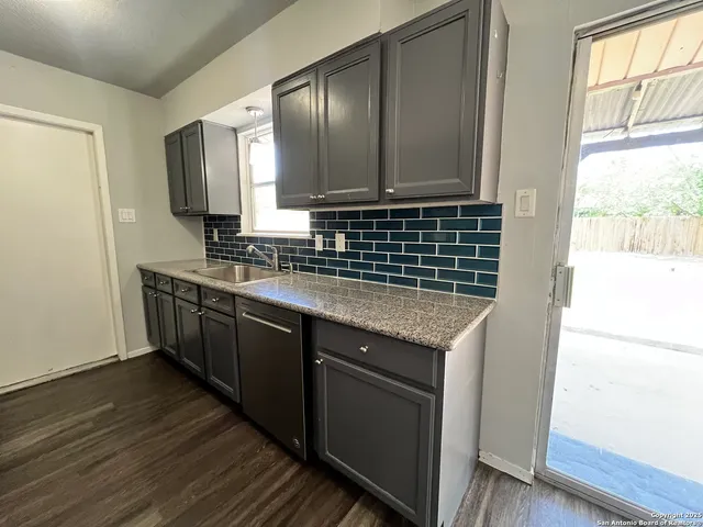 a kitchen with granite countertop cabinets stainless steel appliances a sink and a window