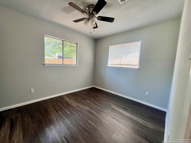 a view of an empty room with a window and wooden floor