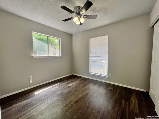 a view of an empty room with window and wooden floor