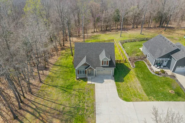 an aerial view of a house with swimming pool and large trees