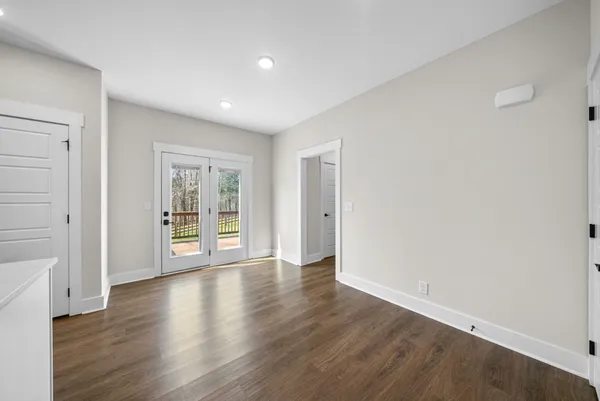 a view of an empty room with wooden floor and windows