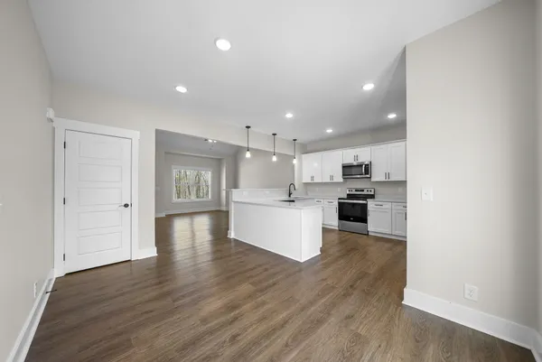 a view of kitchen with kitchen island wooden floors and stainless steel appliances