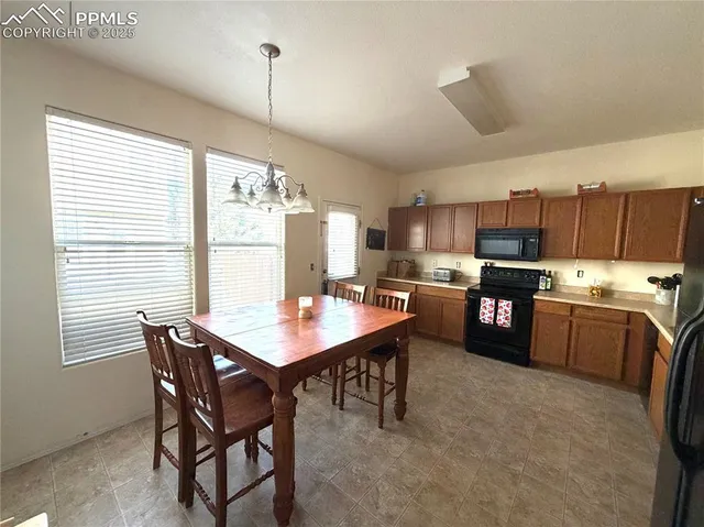 a room with stainless steel appliances kitchen island granite countertop a stove a sink a dining table and chairs