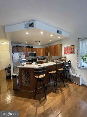 a room with stainless steel appliances kitchen island granite countertop a table chairs sink and cabinets