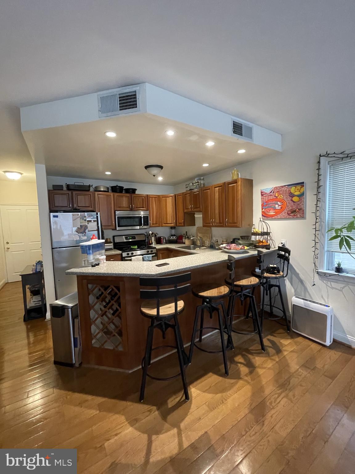 a room with stainless steel appliances kitchen island granite countertop a table chairs sink and cabinets