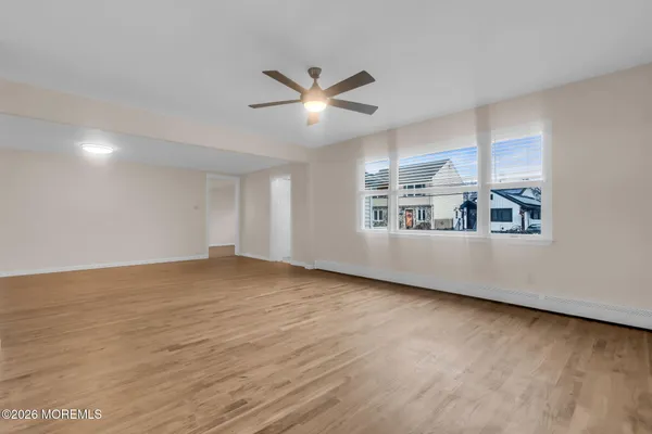 a view of an empty room with window and wooden floor