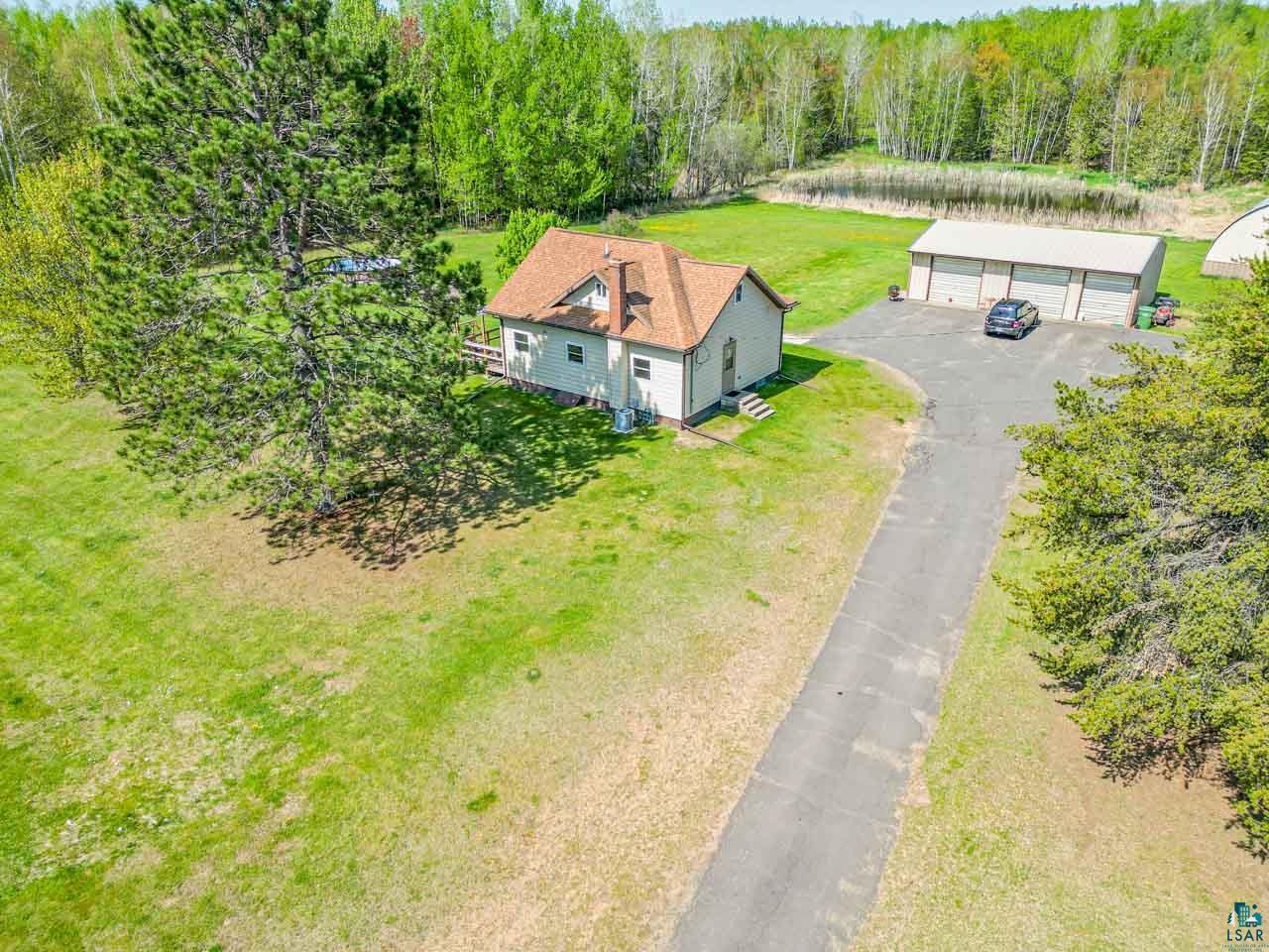 2581 O'Rourke Road Hibbing, MN 55746 - Photo 1 of 61 Property featuring a light-colored exterior, brown shingle roof, and multiple large trees