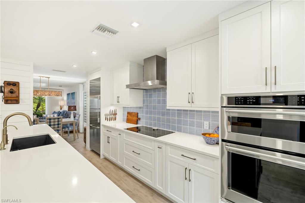 1060 6th Street South, Unit 1060 Naples, FL 34102 - Photo 9 of 26 a kitchen with white cabinets and stainless steel appliances