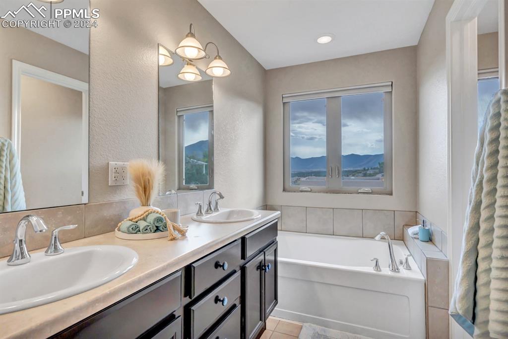 861 Circle Road Palmer Lake, CO 80133 - Photo 19 of 41 a bathroom with a tub double sink window and mirror