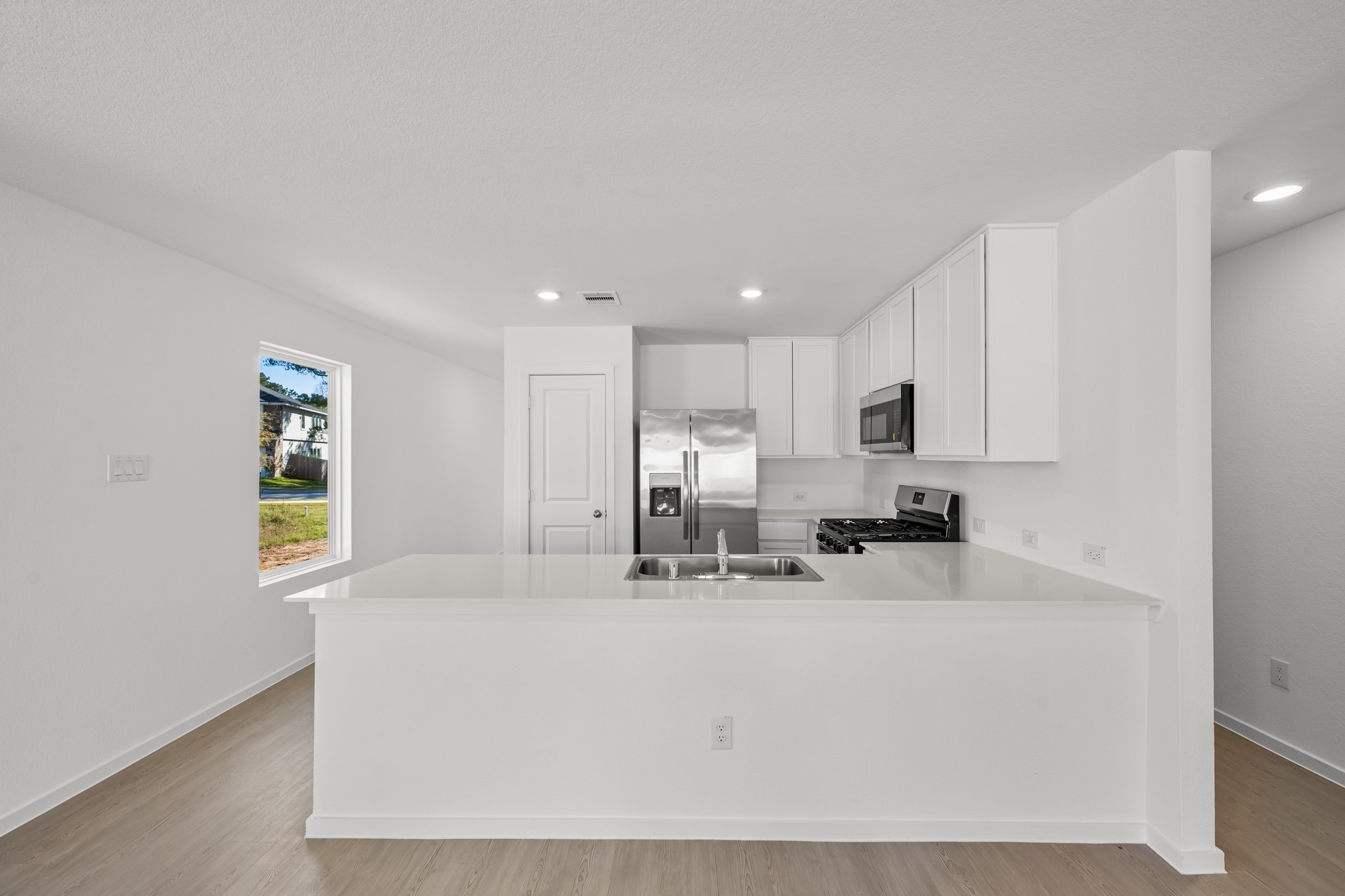 10583 Altitude Way Conroe, TX 77303 - Photo 11 of 33 a kitchen with stainless steel appliances a sink a stove a refrigerator cabinets and a window