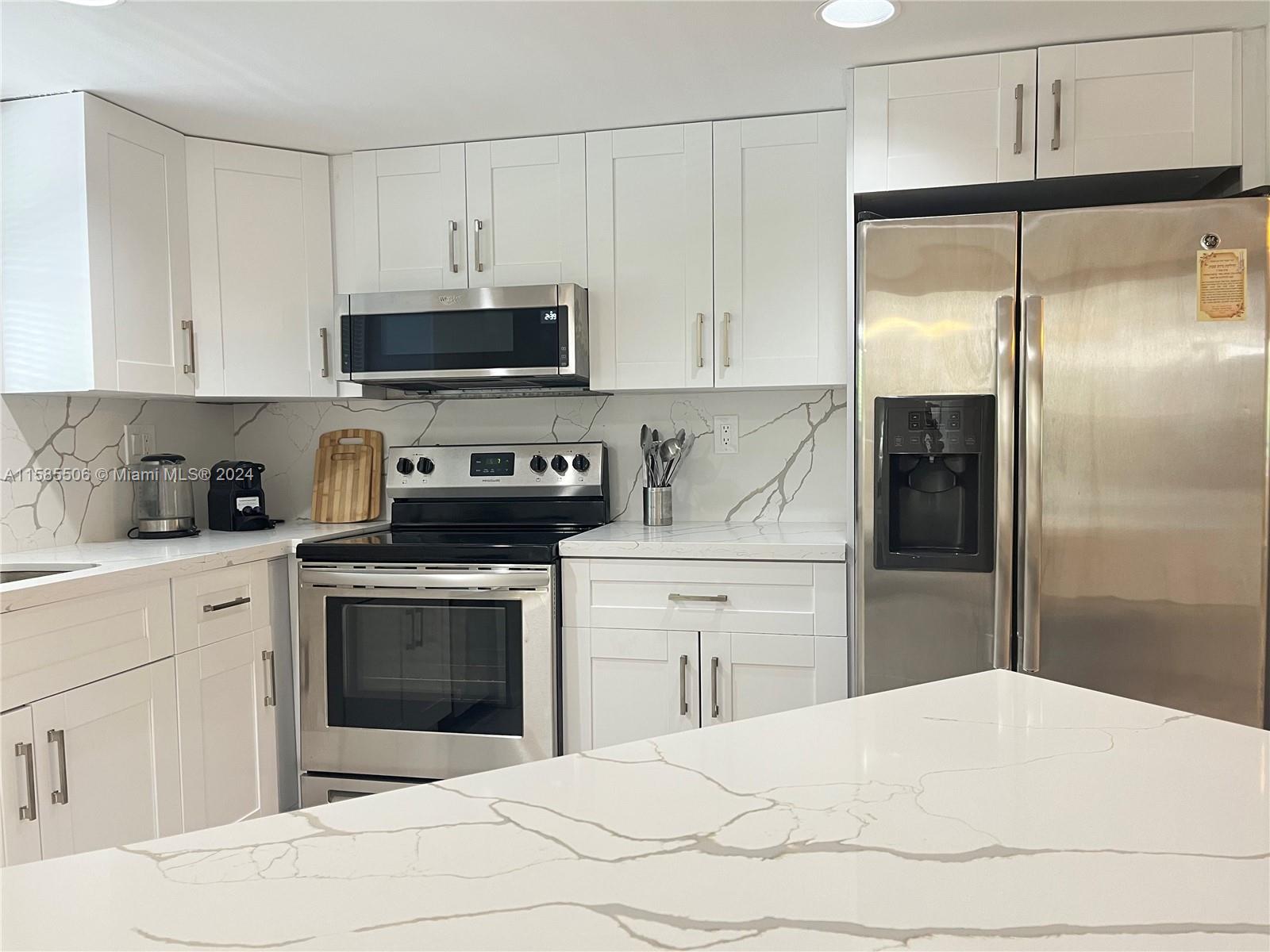 17801 North Bay Road, Unit 303 Sunny Isles Beach, FL 33160 - Photo 2 of 17 a kitchen with a refrigerator sink and white cabinets