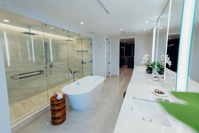 a bathroom with a tub a mirror and shower