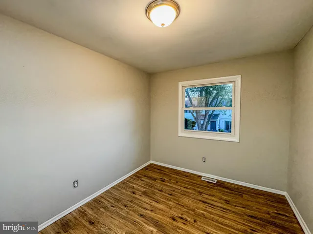 a view of empty room with window and wooden floor