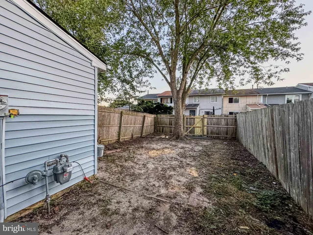 a view of a backyard with wooden fence and large trees