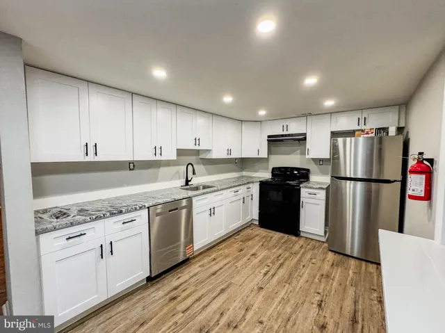 a kitchen with a refrigerator a sink dishwasher and a stove with wooden floor