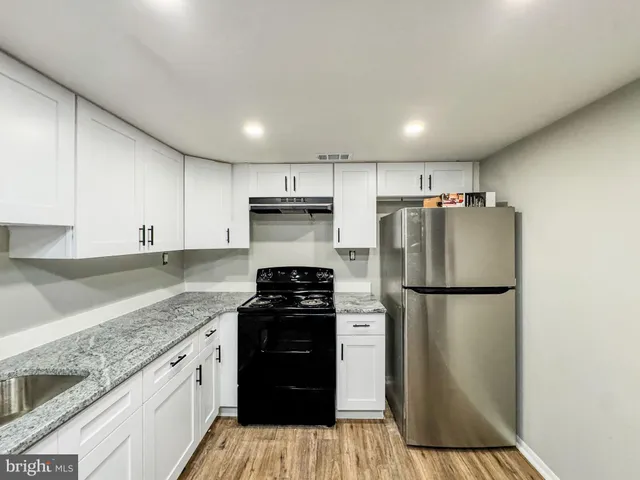 a kitchen with a refrigerator a stove top oven and cabinets