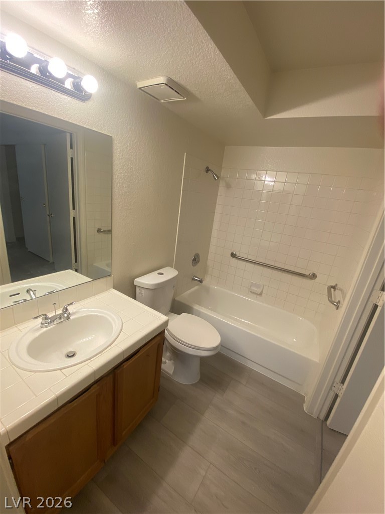 7570 West Flamingo Road, Unit 125 Las Vegas, NV 89147 - Photo 9 of 29 Full bath featuring vanity, a textured ceiling, a textured wall, bathtub / shower combination, and dark wood-type flooring