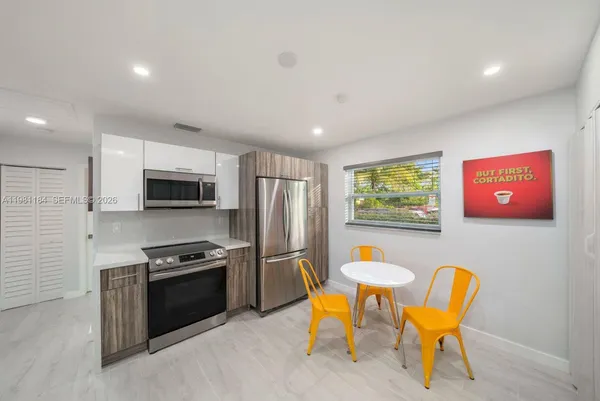 a kitchen with stainless steel appliances kitchen island granite countertop a refrigerator and a dining table