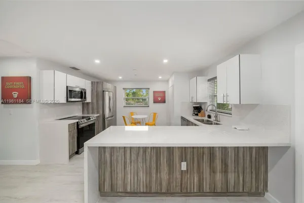 a kitchen with stainless steel appliances a sink a stove a microwave a center island and cabinets