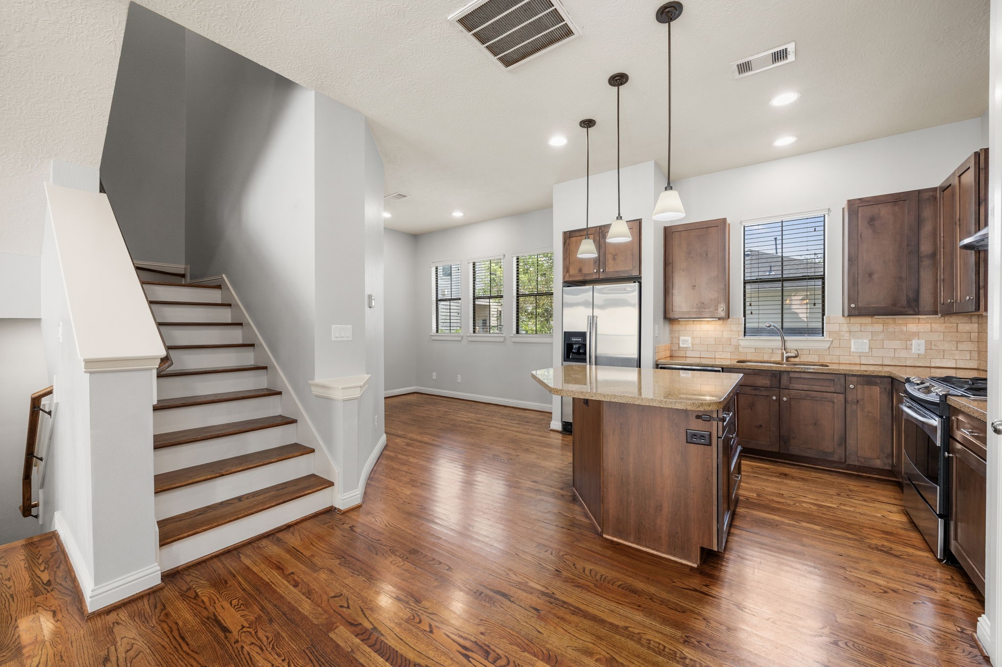 5213 Eigel Street, Unit A Houston, TX 77007 - Photo 13 of 30 a kitchen with stainless steel appliances kitchen island granite countertop wooden floors and a sink