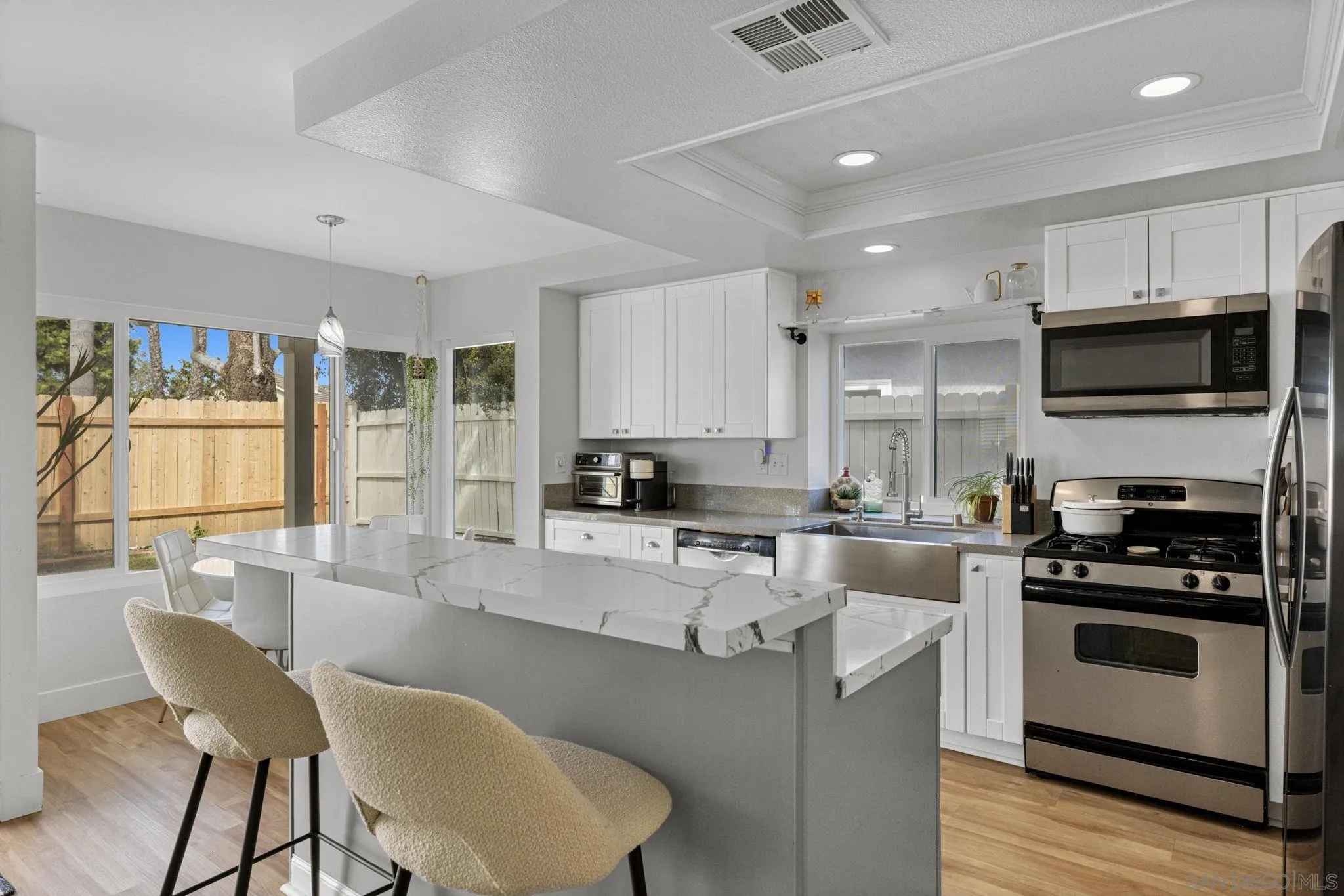 5392 Blackberry Way Oceanside, CA 92057 - Photo 16 of 37 a kitchen with stainless steel appliances granite countertop a stove top oven a sink dishwasher a dining table and chairs with wooden floor