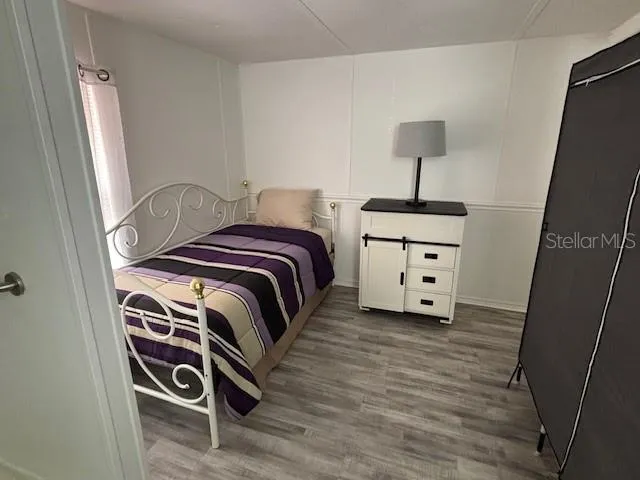 a bedroom with a bed and a lamp on dresser