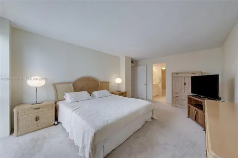 a bedroom with a large bed and a flat tv screen on a dresser