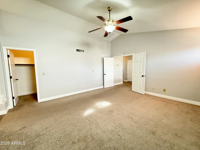 an empty room with closet and a ceiling fan