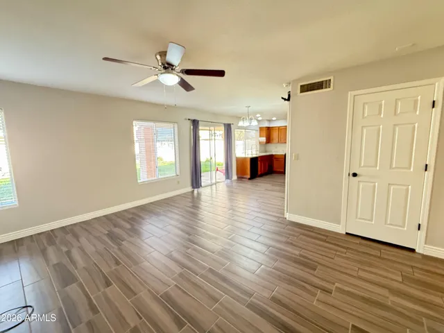 a view of an empty room with window wooden floor and a kitchen
