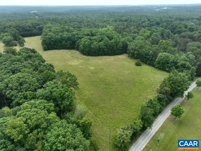 an aerial view of residential houses with outdoor space and trees