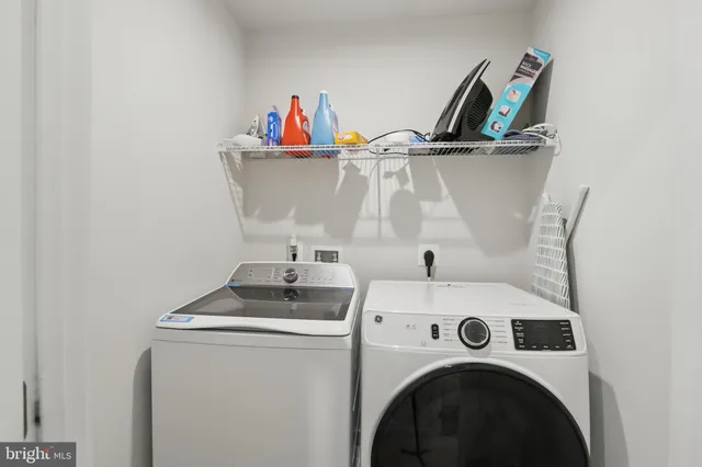 a utility room with dryer washer and a view of living room
