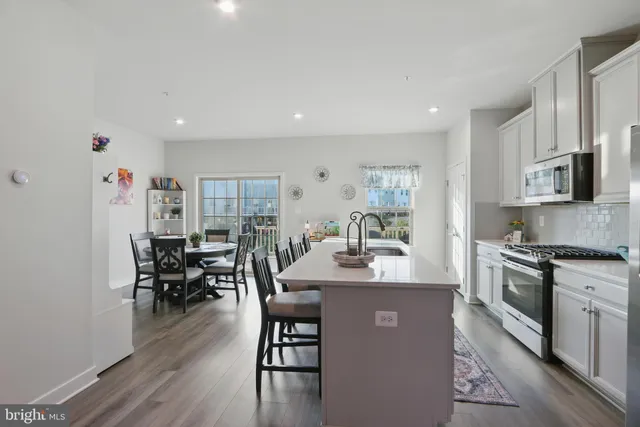 a living room with stainless steel appliances granite countertop furniture a wooden floor and a sink