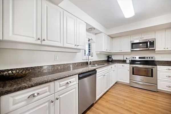 a kitchen with granite countertop white cabinets and white appliances