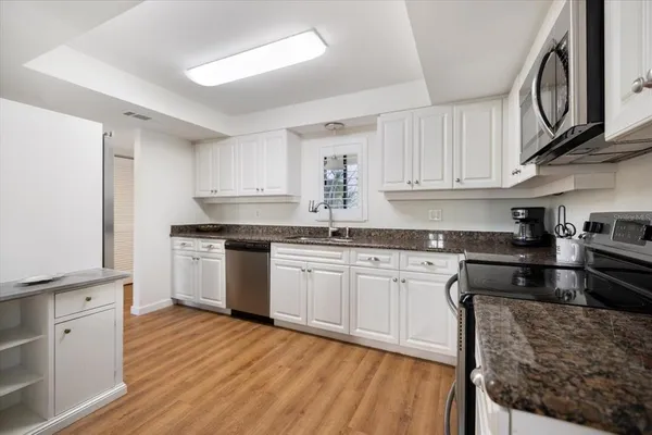 a kitchen with granite countertop white cabinets and white appliances