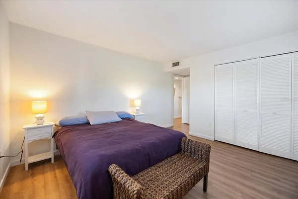 a spacious bedroom with a bed and wooden floor