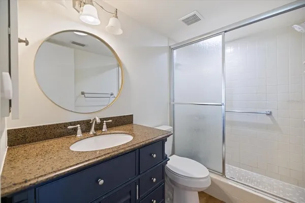 a bathroom with a granite countertop sink toilet and a mirror