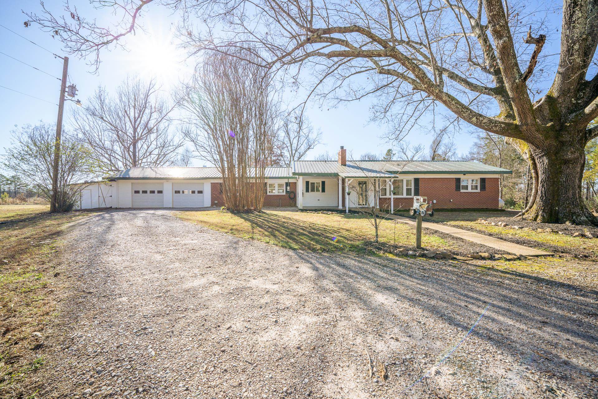 Ranch-style house featuring a chimney, driveway, a garage, a front lawn, and covered porch