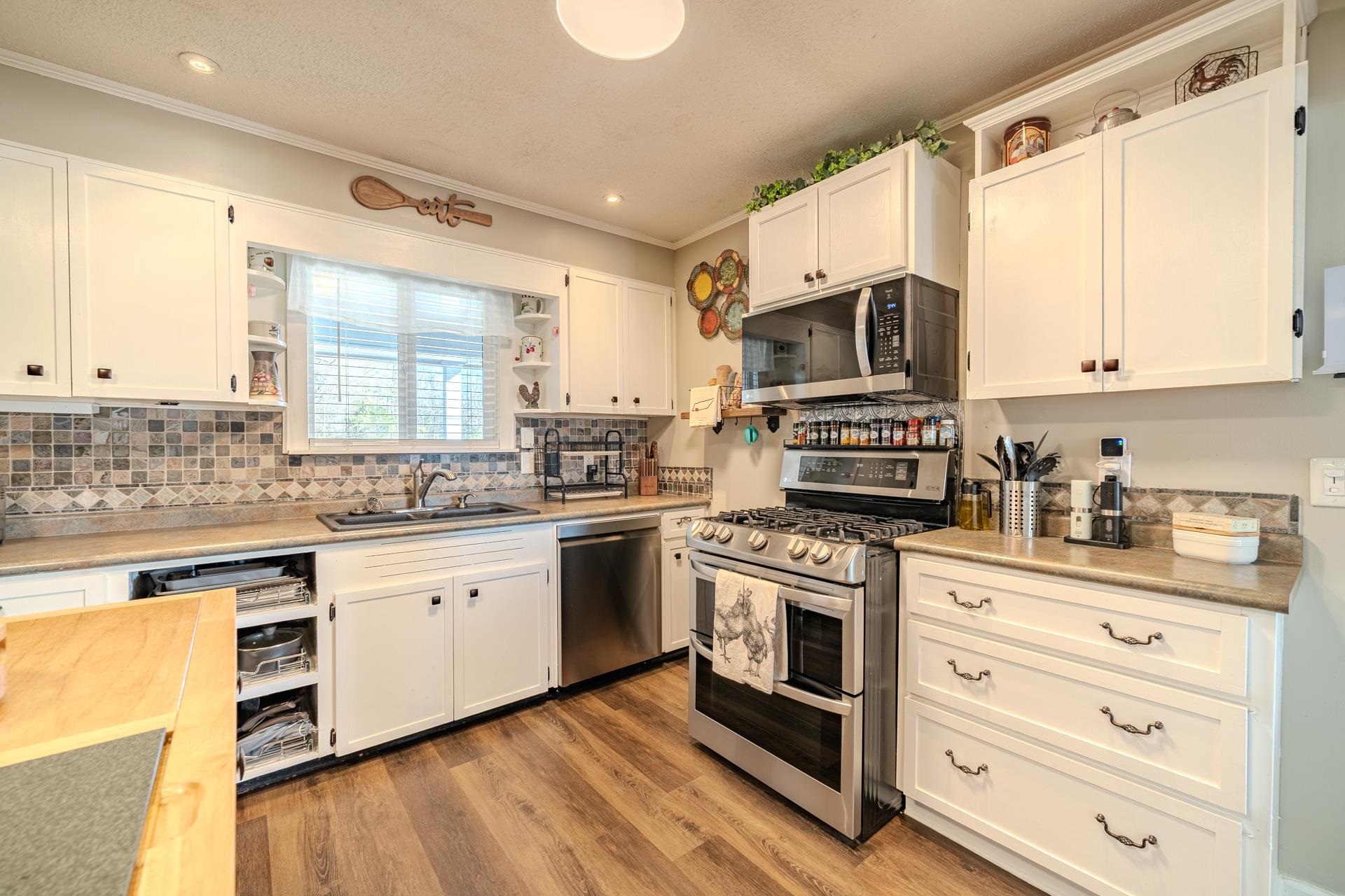 865 Pickett Road Stantonville, TN 38379 - Photo 15 of 40 a kitchen with stainless steel appliances granite countertop a stove top oven a sink dishwasher and white cabinets with wooden floor