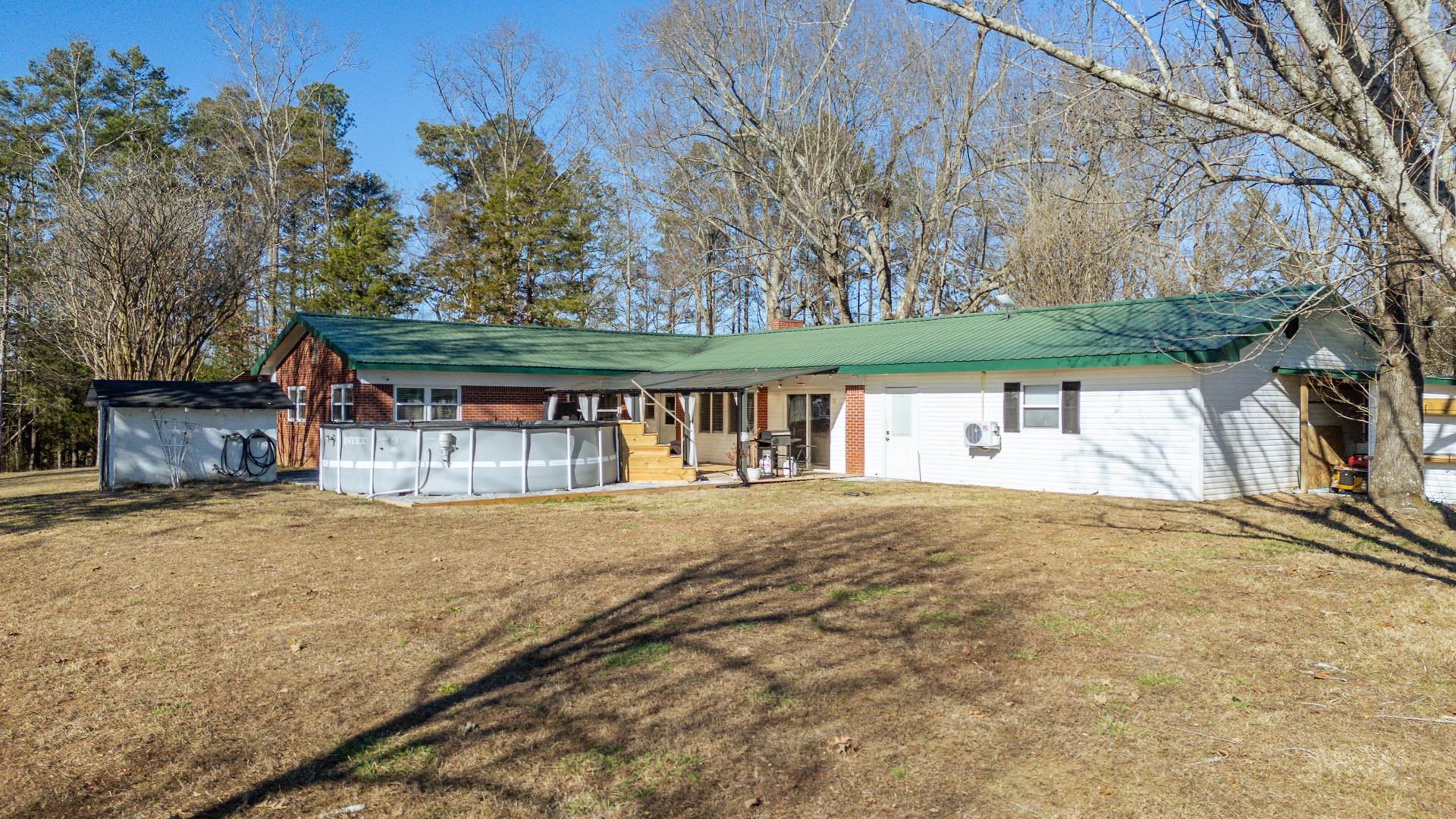 865 Pickett Road Stantonville, TN 38379 - Photo 3 of 40 View of front of house featuring a covered pool, a front lawn, brick siding, a shed, and a chimney