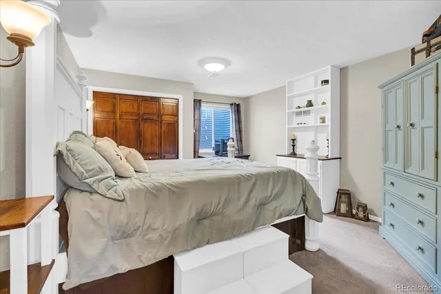 a bed sitting in a bedroom next to a window with dresser and mirror