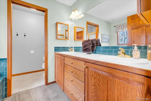 a bathroom with a granite countertop double vanity sink a mirror and a bathtub