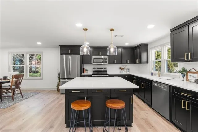 a kitchen with stainless steel appliances a sink a stove a refrigerator cabinets and dining table