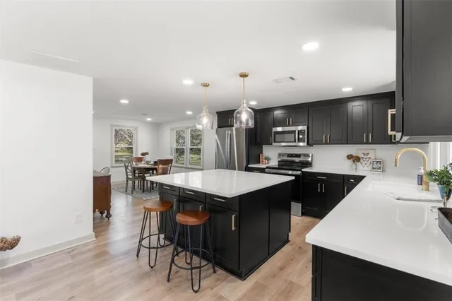 a kitchen with stainless steel appliances granite countertop a table chairs sink refrigerator and cabinets