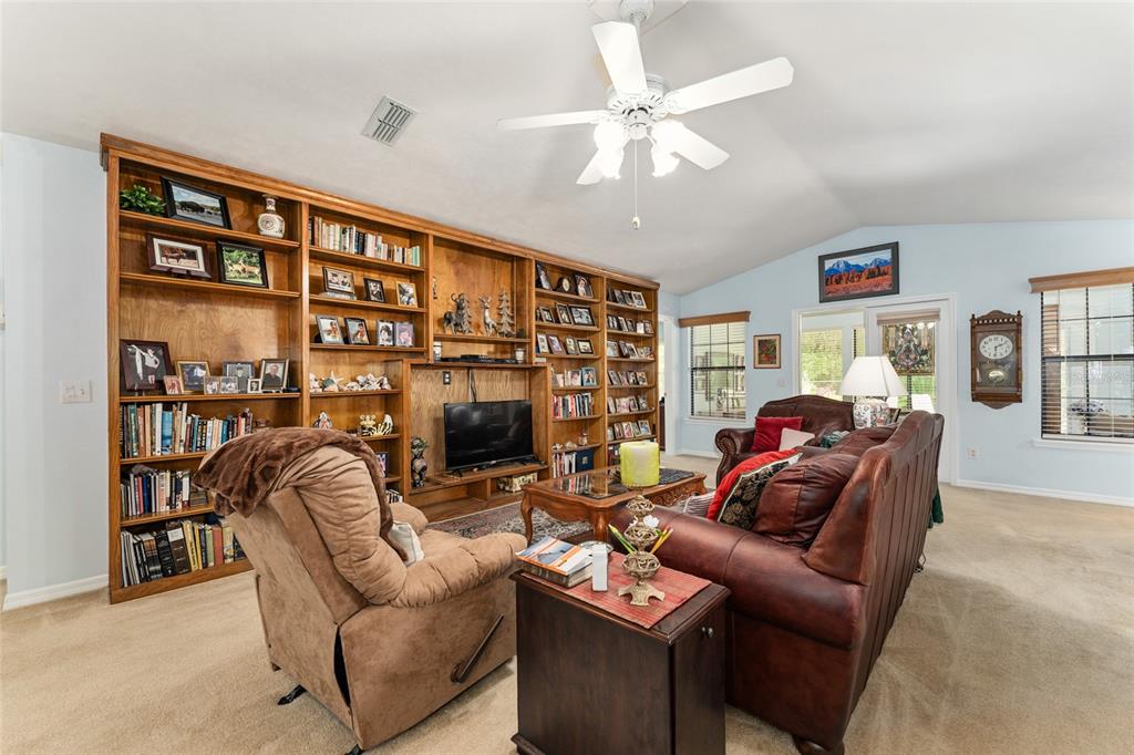 10922 Palmetto Boulevard Alachua, FL 32615 - Photo 9 of 51 a living room with furniture a ceiling fan and a bookshelf