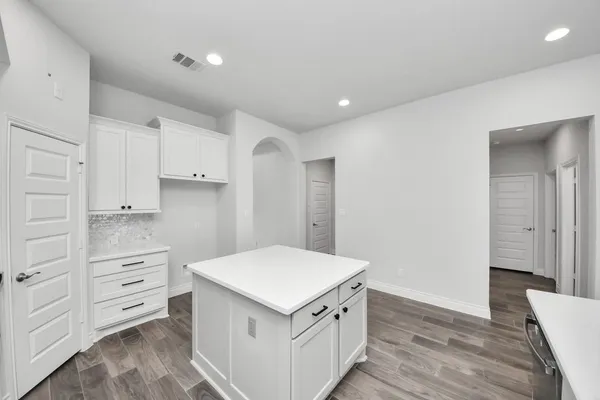 a kitchen with granite countertop a stove cabinets and wooden floor